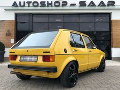 a yellow car is parked in front of a autoshop saar building with its door open