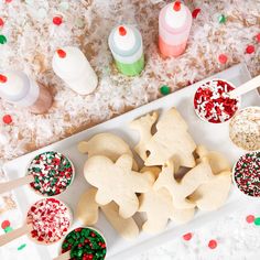 there are many cookies on the plate with spoons next to them and sprinkles