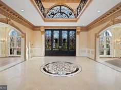 an ornate entry way with glass doors and chandelier above the door is a circular marble floor