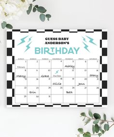 a black and white checkered baby's birthday calendar on a table next to flowers