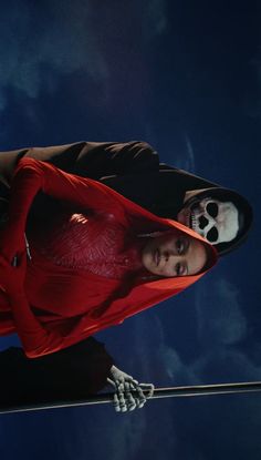 a man in a red shirt is holding onto a pole with a skull on it