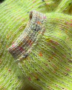 a close up view of a green knitted object with small speckles on it