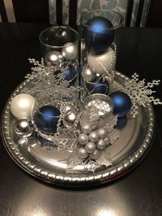 silver and blue christmas decorations on a metal platter with candlesticks, balls and snowflakes