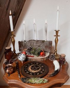 a wooden table topped with candles and an old fashioned clock on it's side