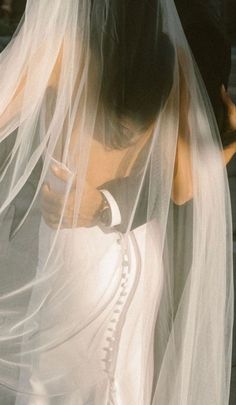 a woman in a wedding dress and veil is looking at her cell phone with the screen showing