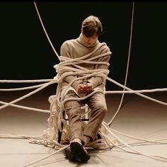 a woman wrapped in rope sitting on top of a chair