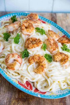 pasta with shrimp and parsley in a blue bowl on a wooden table, ready to be eaten