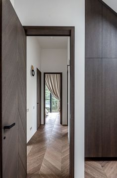 an open door leading to a hallway with wooden floors and walls, along with a large window