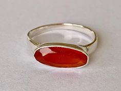 Sterling silver & carnelian ring  Carnelian oval faceted gemstone bezel set in sterling silver Highest quality 925 sterling silver (92.5% pure silver) & carnelian No two pieces of natural stone are identical. Colour variations and markings in the natural stones makes this a truly unique piece Specifications:    Color: Silver & Orange / Red   Material: 925 Sterling Silver & Carnelian Dimensions of gemstone: 14 mm x 6 mm approximately Weight of ring: 2.3 grams approximately Package Includes: 1 x Sterling silver & gemstone ring with complimentary jewellery pouch Red Oval Moonstone Ring, Oval Red Moonstone Ring Gift, Red Oval Moonstone Ring For Gift, Oval Carnelian Moonstone Ring For Anniversary, Carnelian Ring, Silver Jewelry Rings, Faceted Gemstones, Stackable Rings, Pure Silver