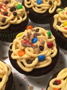 cupcakes with white frosting and colorful candies in the middle on a plate