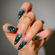 a woman's hand with green and gold nail designs on it, holding onto her ring