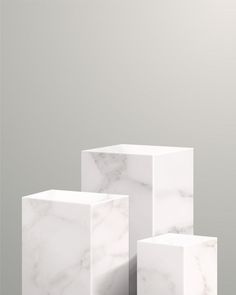 three white cubes sitting on top of each other in front of a gray wall