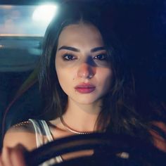 a woman sitting in the driver's seat of a car looking at the camera