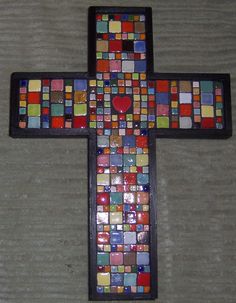 a multicolored cross with a heart on the center is sitting on a table