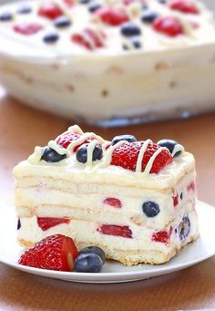 a piece of cake on a plate with berries and blueberries