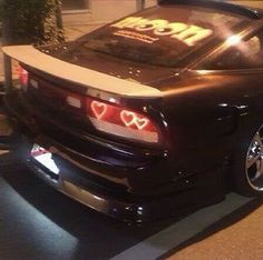 a black sports car parked in front of a building with the word i love you written on it