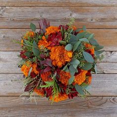 an orange and red bouquet sitting on top of a wooden table