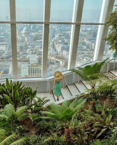 a woman with a straw hat is walking up some stairs in the sky garden at the top of the london eye