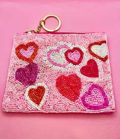 a pink purse with hearts on it and a keychain hanging from the front