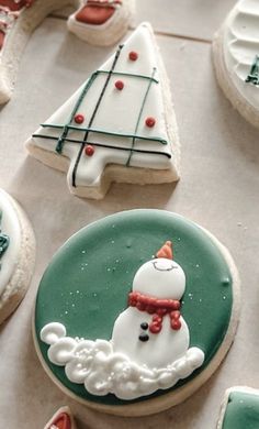 decorated cookies with frosting and icing are arranged on a table top, including one snowman