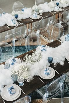 the table is set with blue and white plates, glass vases, and baby's breath flowers