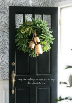 a black door with a wreath and bells on it