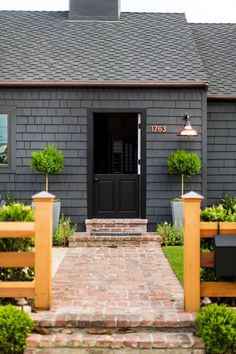 the front door of a gray house with wooden fence and planters on either side