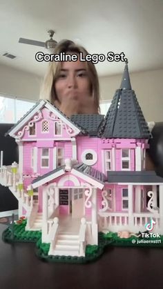 a woman holding up a pink lego house