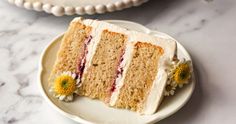 a slice of cake with white frosting and flowers on the side sitting on a plate