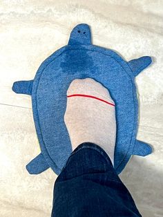 a person standing on the floor with their feet in a fish shaped rug that looks like a shark