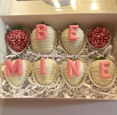 four decorated strawberries in a box with the word be mine spelled out on them