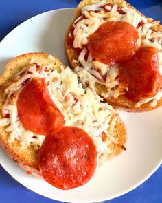 two pieces of bread with pepperoni and cheese on them sitting on a white plate