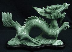 a green dragon statue sitting on top of a black surface