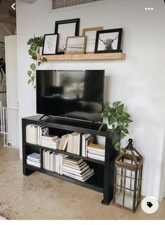 a flat screen tv sitting on top of a black entertainment center next to a wooden shelf filled with books