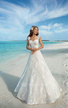 a woman standing on top of a beach next to the ocean wearing a wedding dress