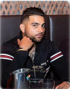 a man sitting at a table with a drink in front of him and looking off to the side