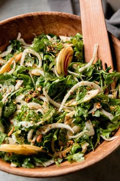 a wooden bowl filled with greens and apple slices