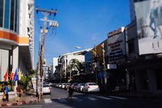 a city street with cars and people walking on the sidewalk