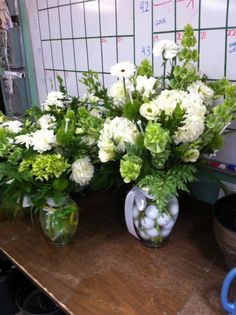 two vases filled with white and green flowers