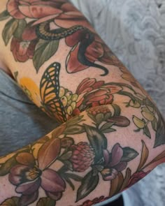 a woman's arm with tattoos and flowers on her arms, both covered in butterflies