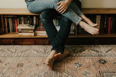 a man sitting on top of a wooden bench in front of a book shelf filled with books