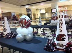 balloons and footballs are on the tables at a sports event