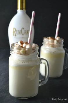 two mason jars filled with hot chocolate and marshmallows next to a bottle of rum