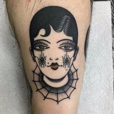 a woman's face with spider webs and eyes on her leg, done by tattoo artist