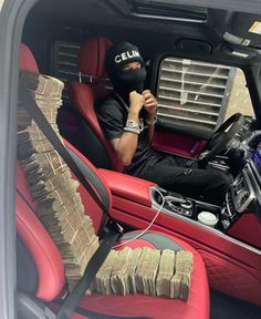 a man sitting in the driver's seat of a car with stacks of money