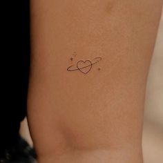 a small tattoo on the back of a woman's left arm, which has an intertwined heart and stars