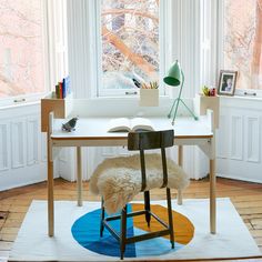 a desk with a chair and a book on it in front of a large window