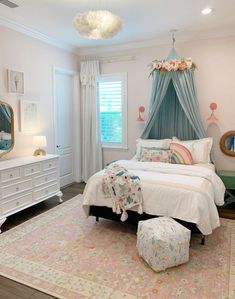 a bedroom with a canopy bed, dresser and mirror in the corner next to it