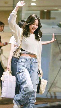 a woman in high waisted jeans is waving