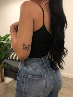 a woman with a butterfly tattoo on her left arm and right hand behind her back